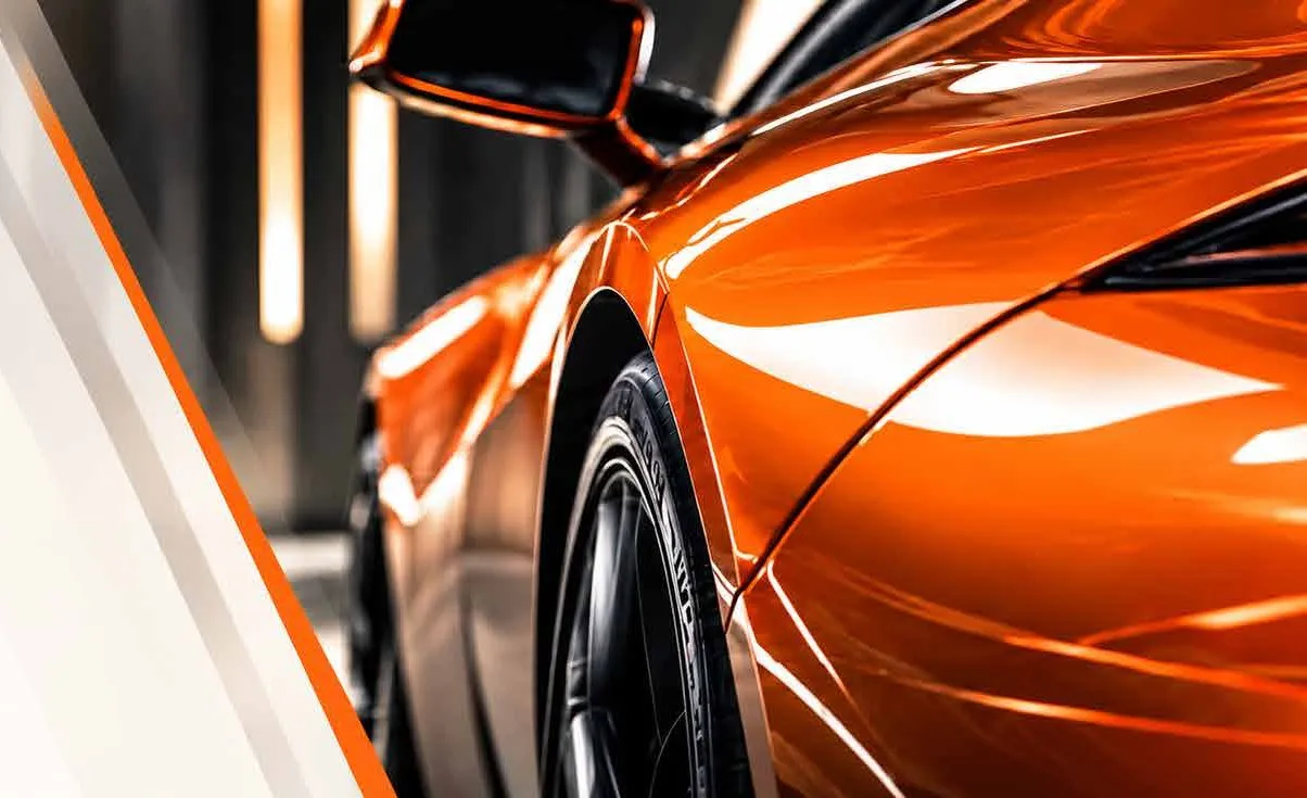Coche deportivo recién pintado en naranja metalizado bajo la luz del taller
